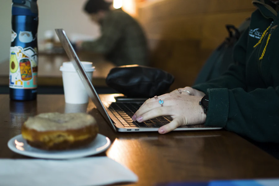Ilustrasi seseorang sedang menggunakan laptop di kafe dengan jaringan Wi-Fi publik.